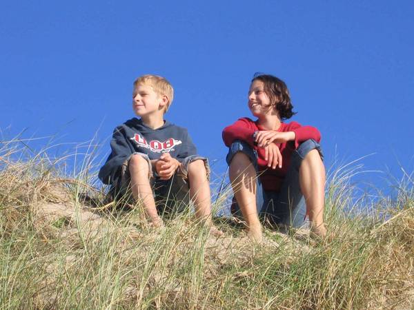 Mädchen und Junge sitzen auf Düne